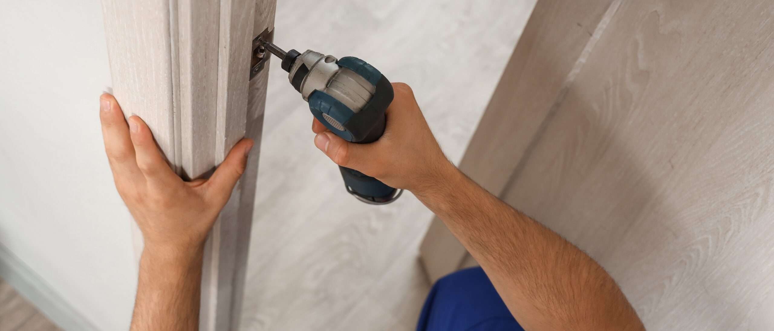 Male,Worker,With,Electric,Drill,Installing,Door,Strike,Plate,At Male,Worker,With,Electric,Drill,Installing,Door,Strike,Plate,At